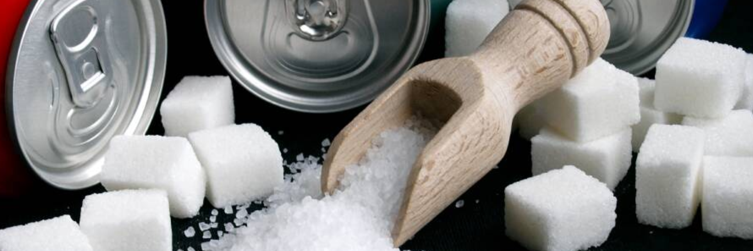 Soda cans next to sugar cubes, illustrating the high sugar content in sugary beverages and their negative impact on health.